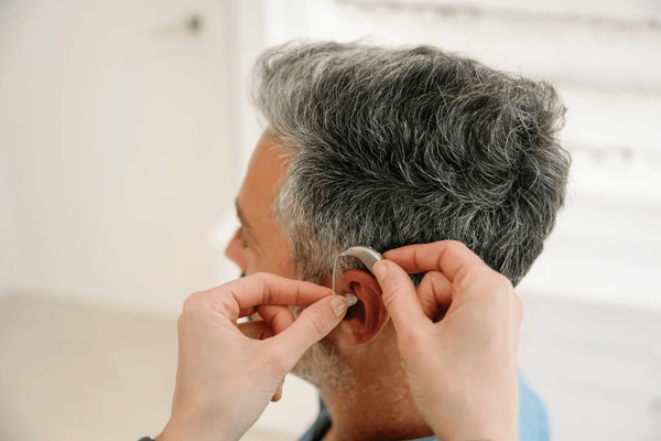 audiologist assisting client hearing aid 600nw 2633891393